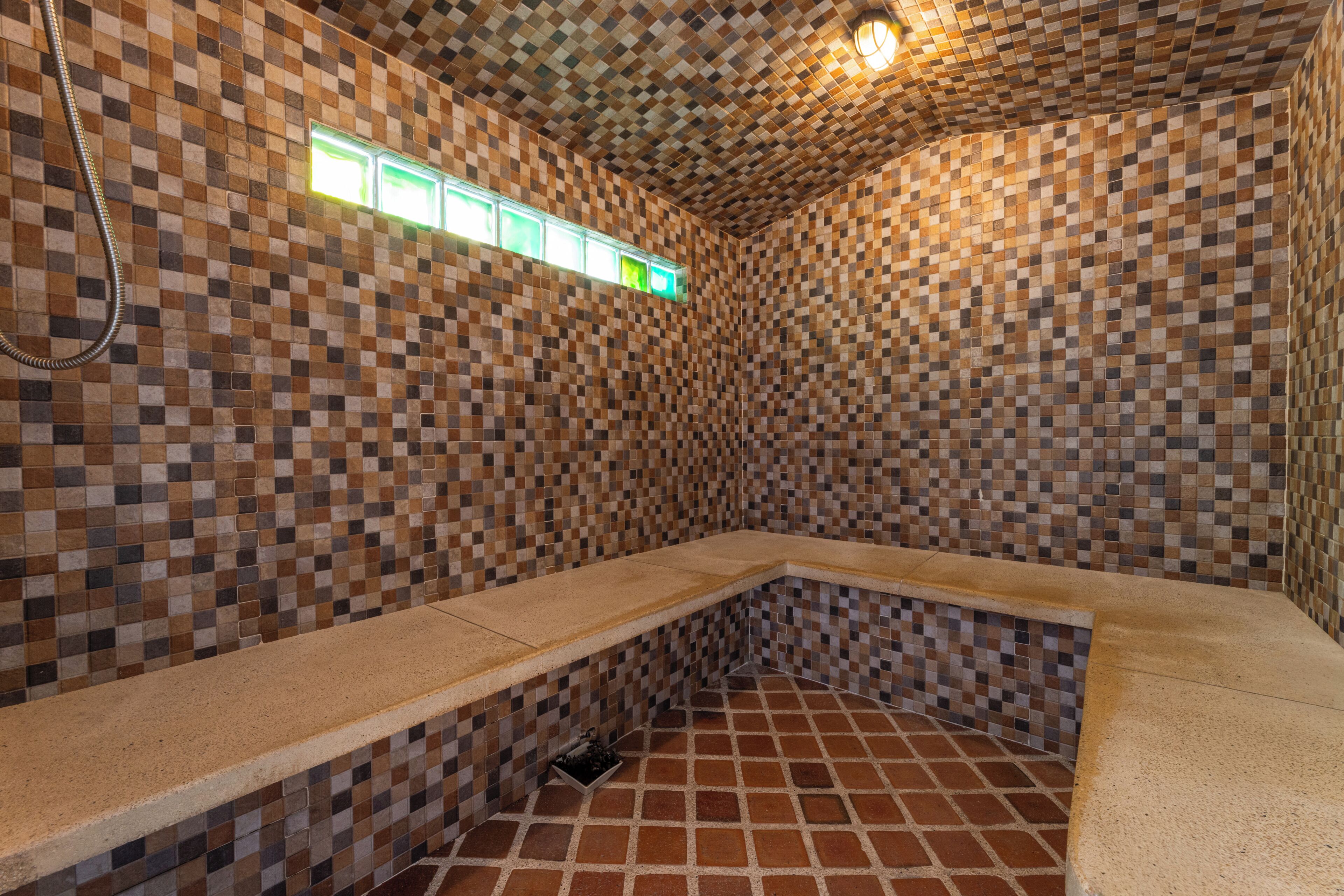 A tiled room with a bench, a shower, and a window.
