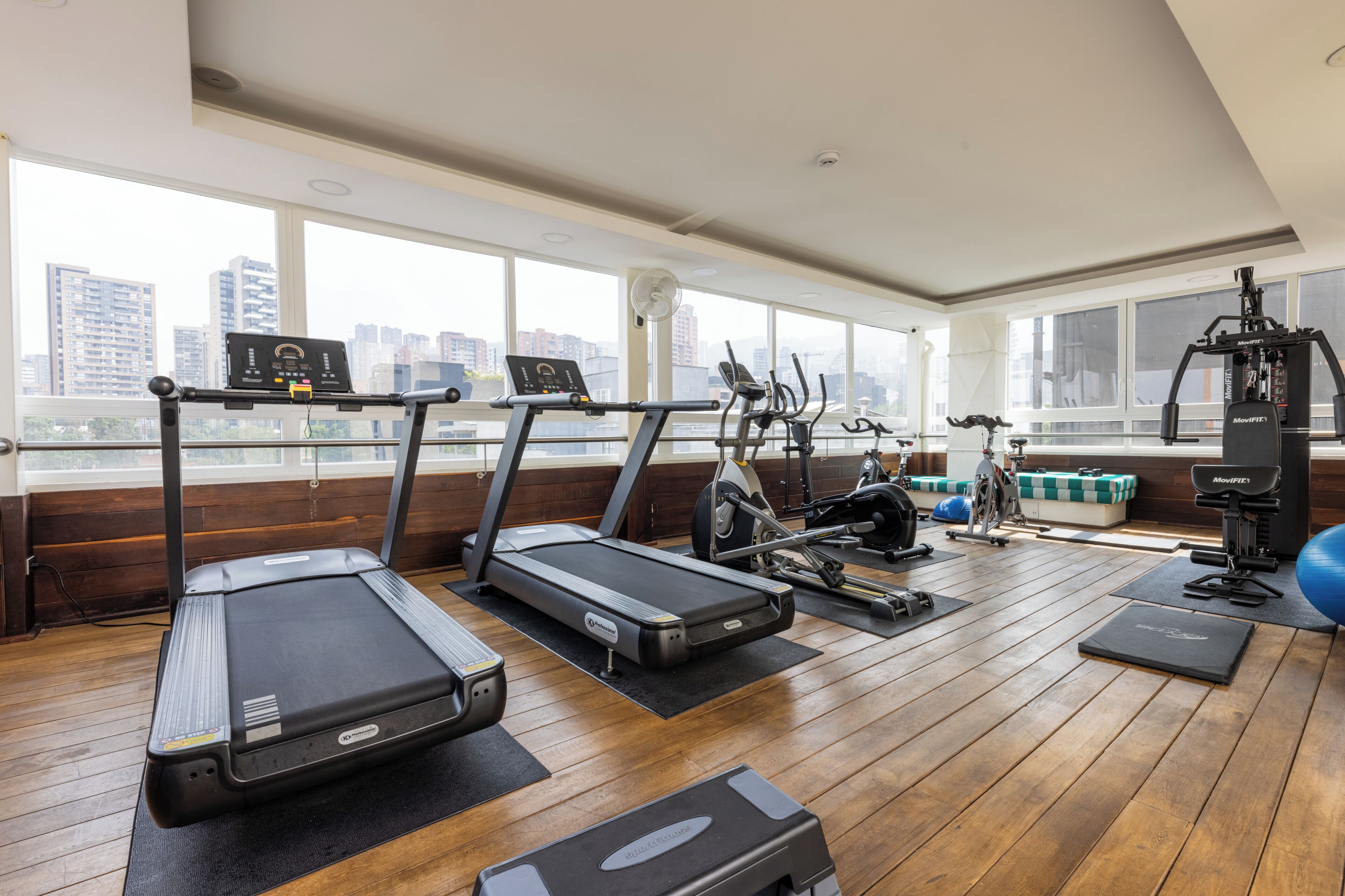 Un gimnasio con cintas de correr, elípticas y equipamiento de ejercicio.