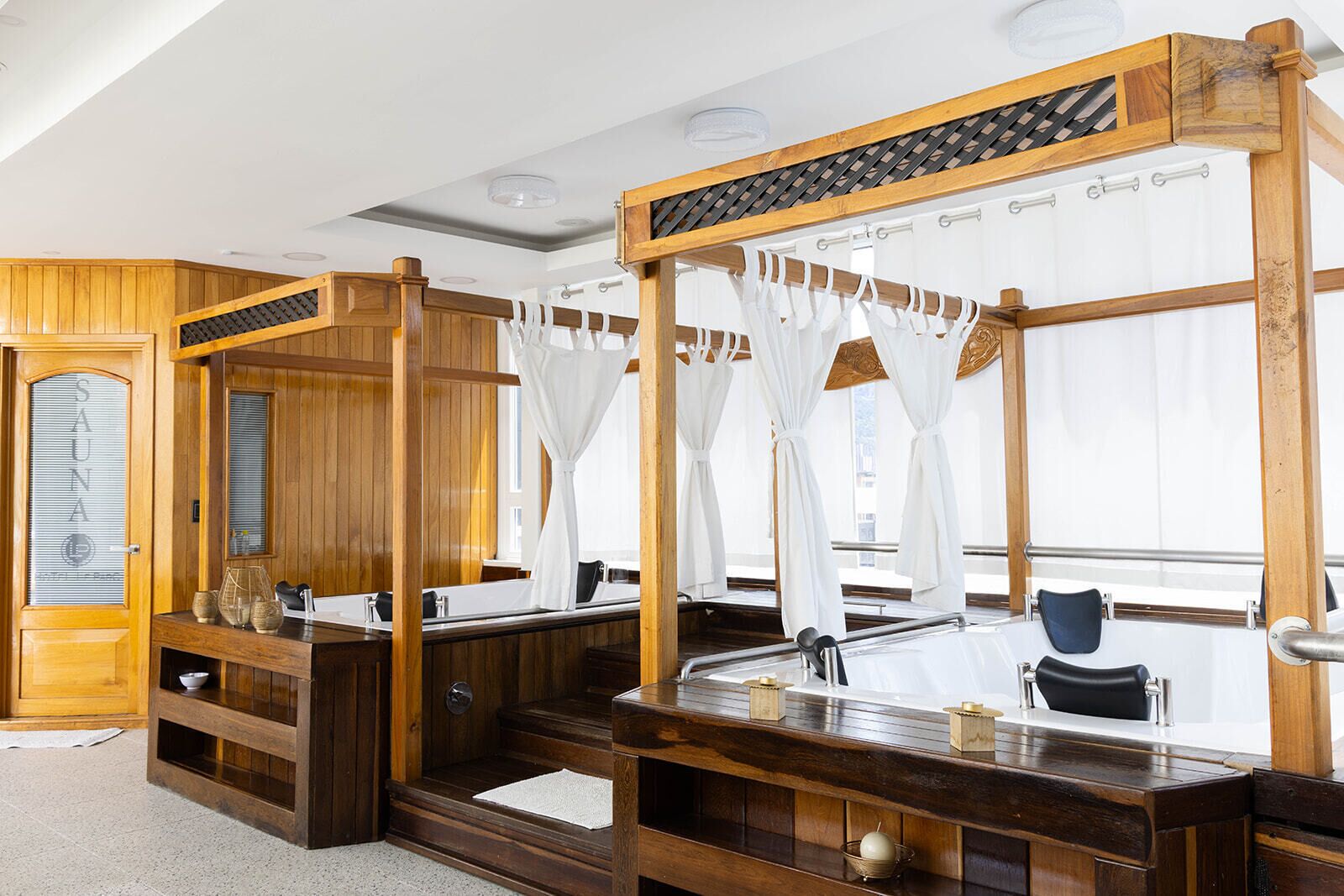 Un spa con paredes de madera, un espejo grande, una banca de madera y una cama con dosel.