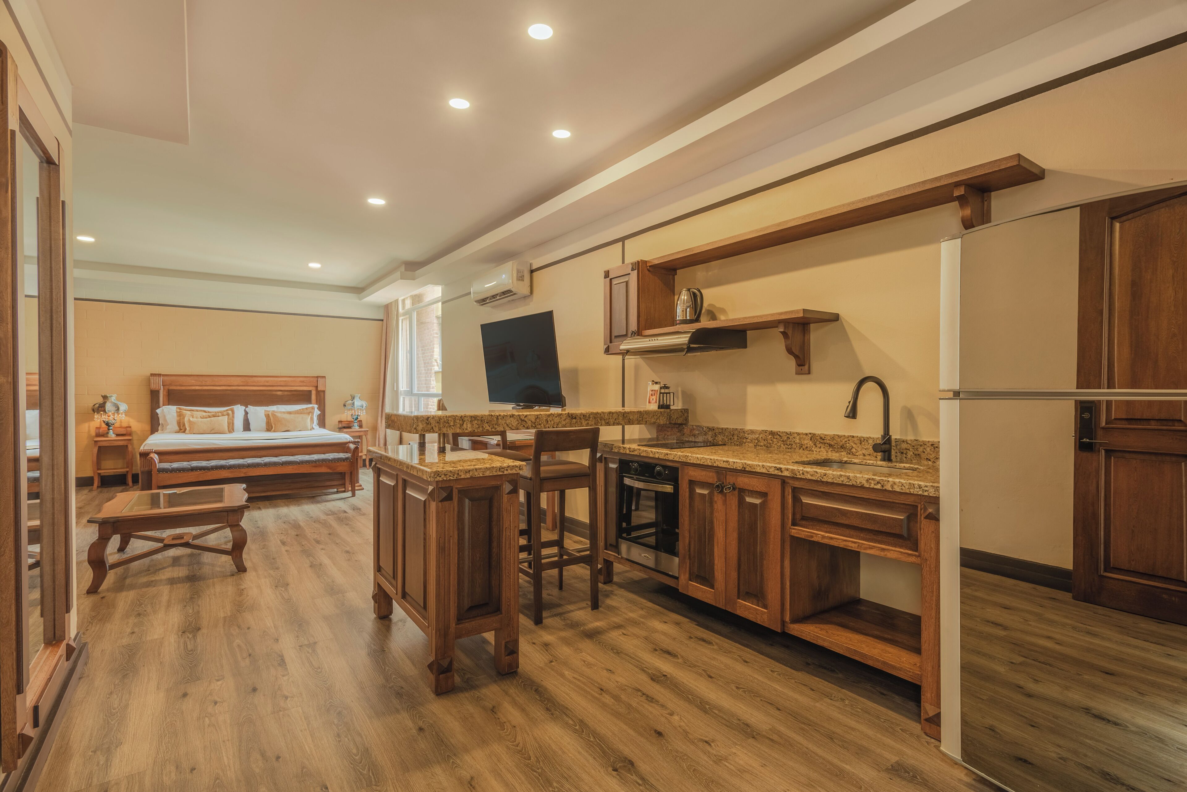 A compact kitchen with wooden cabinets, a built-in oven, and a dining area with a bench.