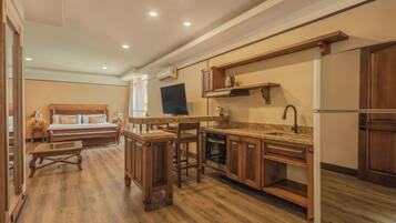 A compact kitchen with wooden cabinets, a built-in oven, and a dining area with a bench.