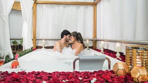 A couple in a bathtub surrounded by rose petals and candles. - Hotel Du Parc (Medellín)