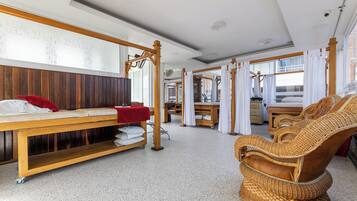Una habitación con un banco de madera, una silla de mimbre y una cama con sábanas blancas.