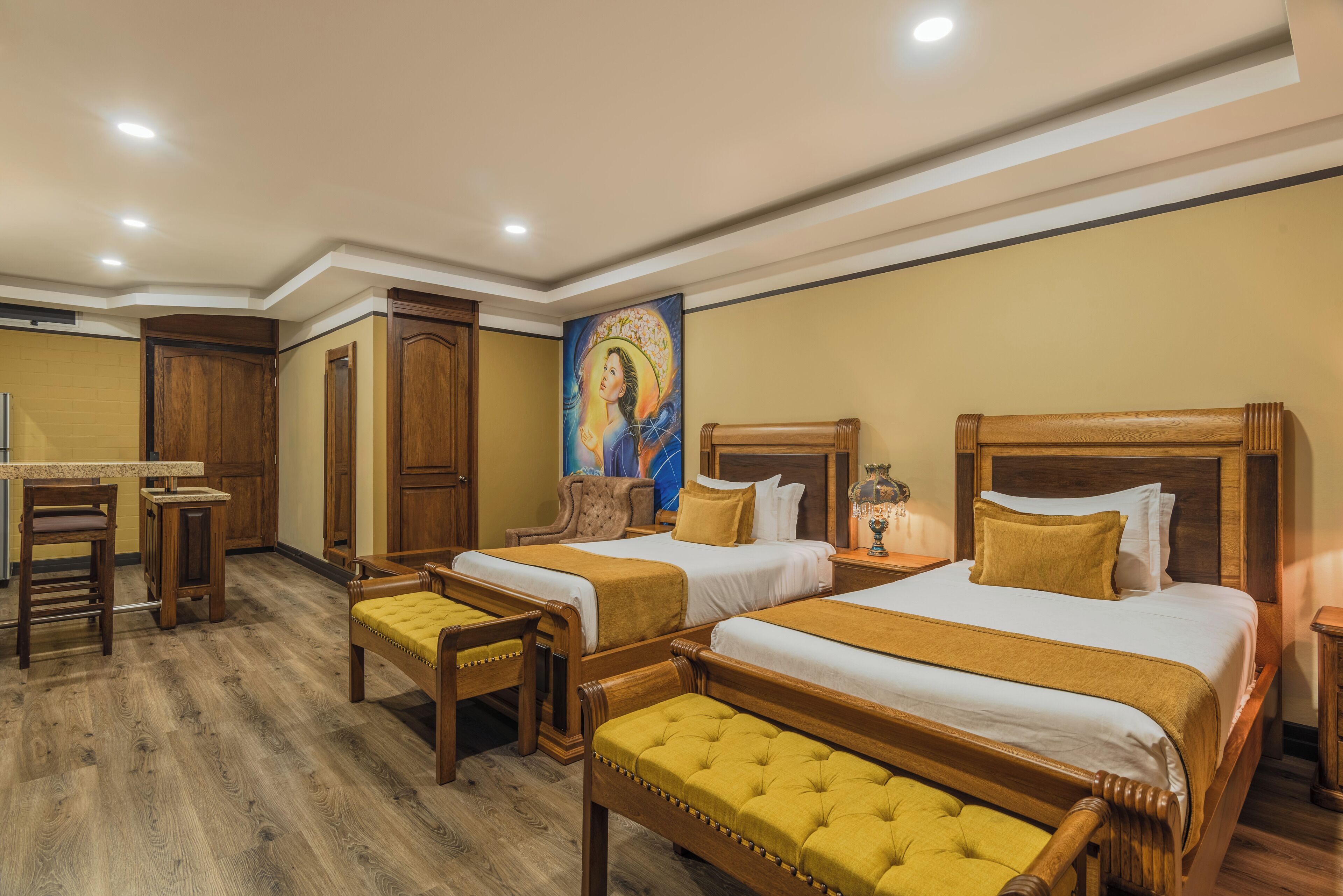 A hotel room with two beds, a desk, and a painting on the wall.