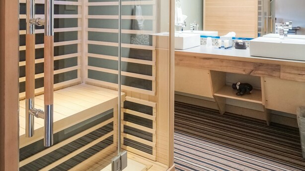 A modern bathroom with a glass-enclosed shower, wooden cabinetry, and a large mirror.