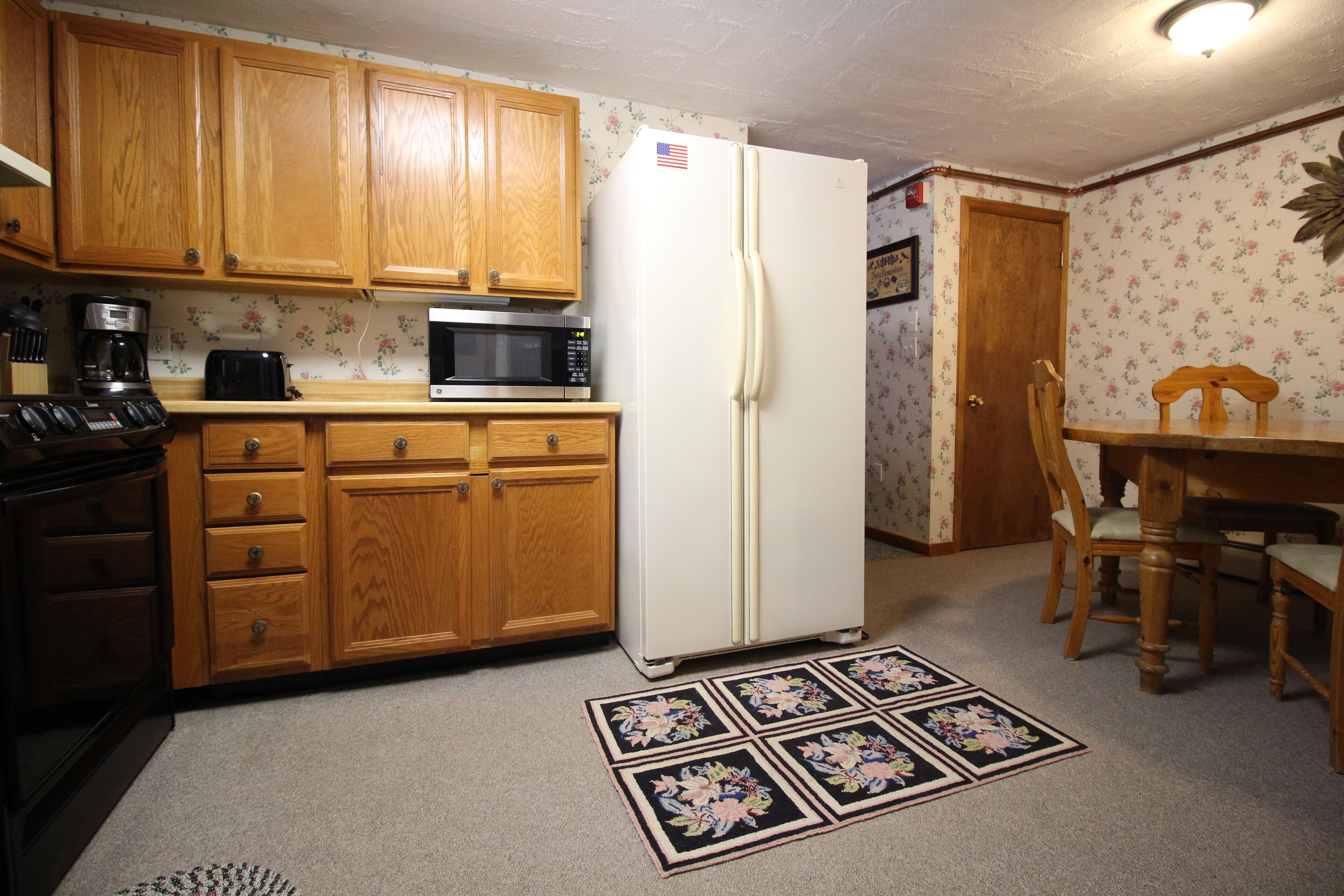 A kitchen with wooden cabinets, a white refrigerator, a microwave, a toaster, and a coffee maker.