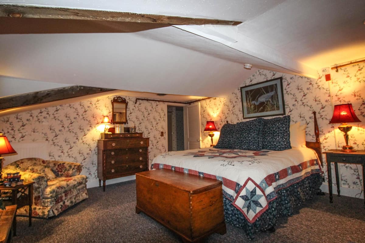 A bedroom with a bed, dresser, nightstand, and a wooden chest.