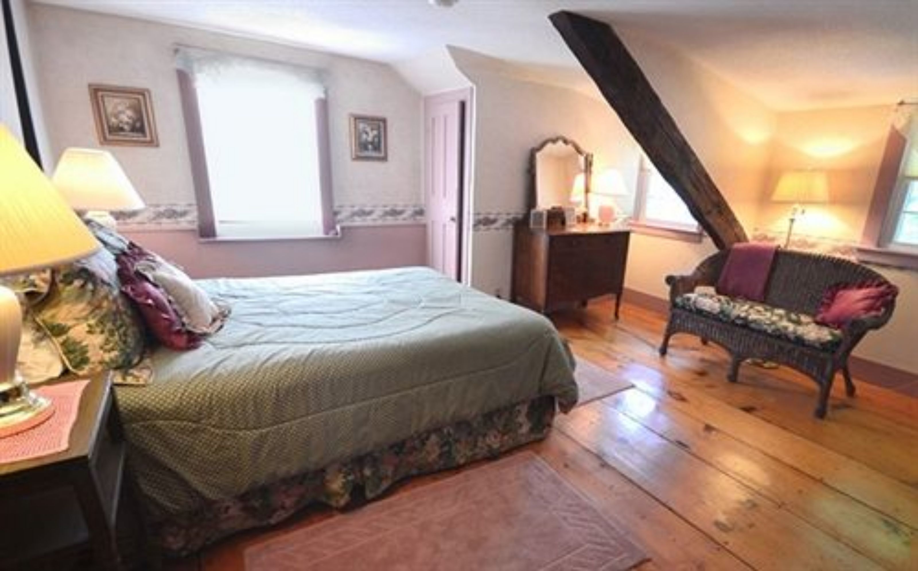 A bedroom with a bed, a chair, a dresser, and a window.