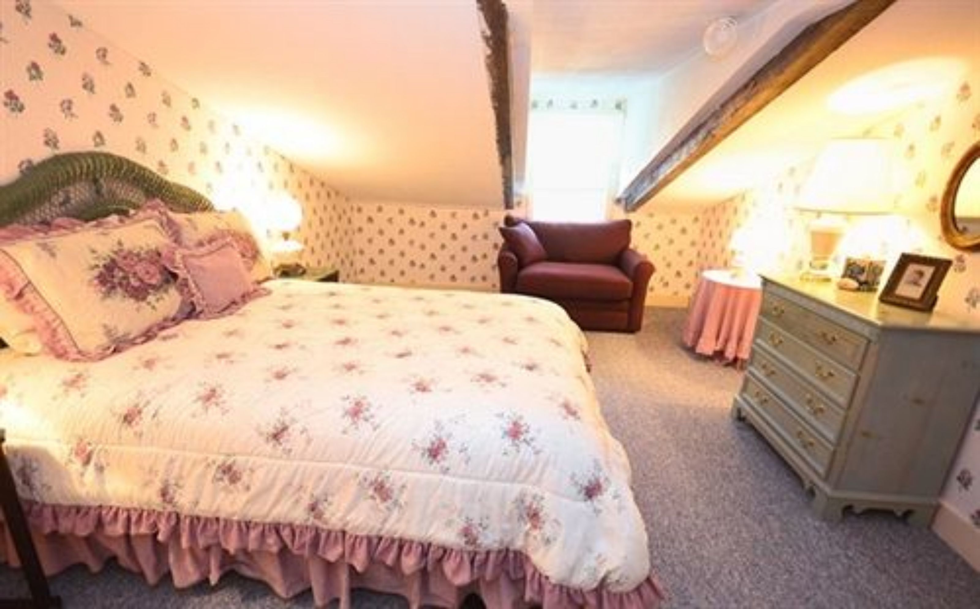 Une chambre à coucher avec un lit, une commode, une chaise et une lampe.