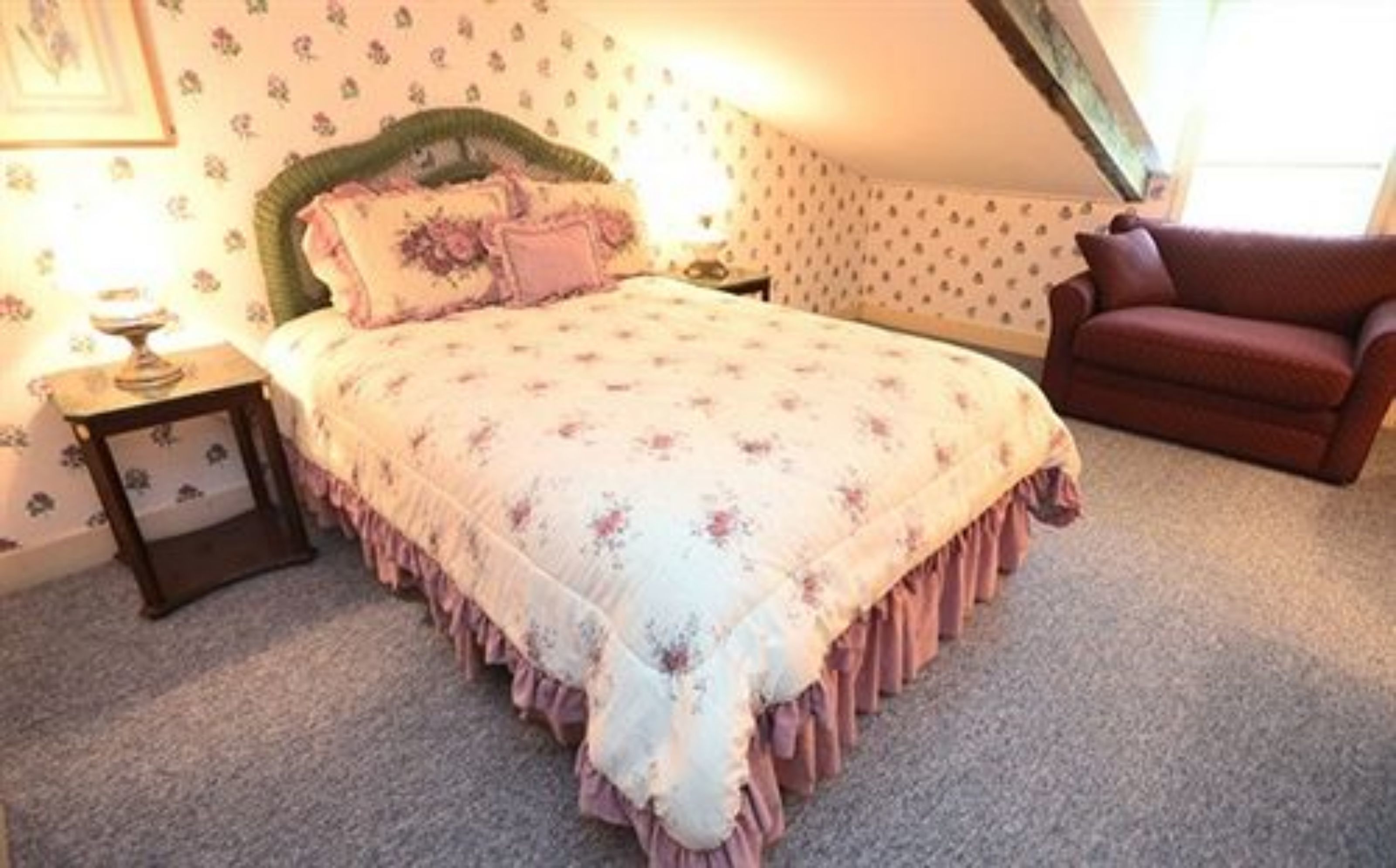 Une chambre à coucher avec un lit, une table de chevet, une chaise et une fenêtre.