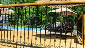 A pool area with a metal fence, a bench, and a covered seating area. - The Nutmeg Inn (Meredith)
