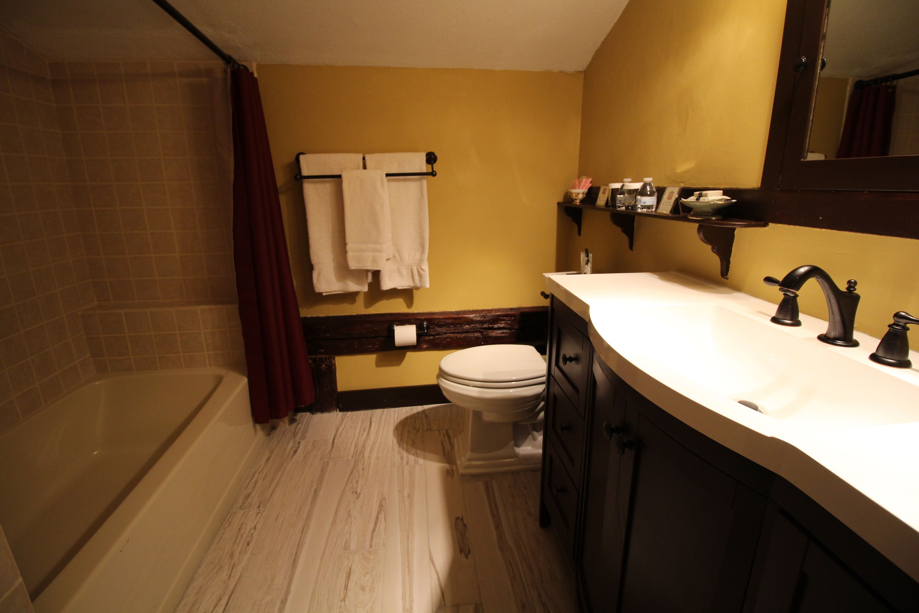 Un baño con bañera, inodoro, lavamanos y espejo.