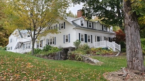 A large white house with a stone foundation, a front porch, and a staircase leading to the entrance. - The Nutmeg Inn (Meredith)
