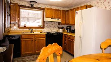A kitchen with wooden cabinets, a stove, a sink, and a refrigerator.