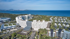 A modern hotel with a curved facade, located near a coastline with a view of the sea.