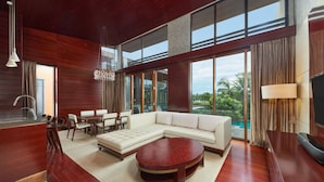 A spacious living area with a large sectional sofa, a round coffee table, and a dining set.