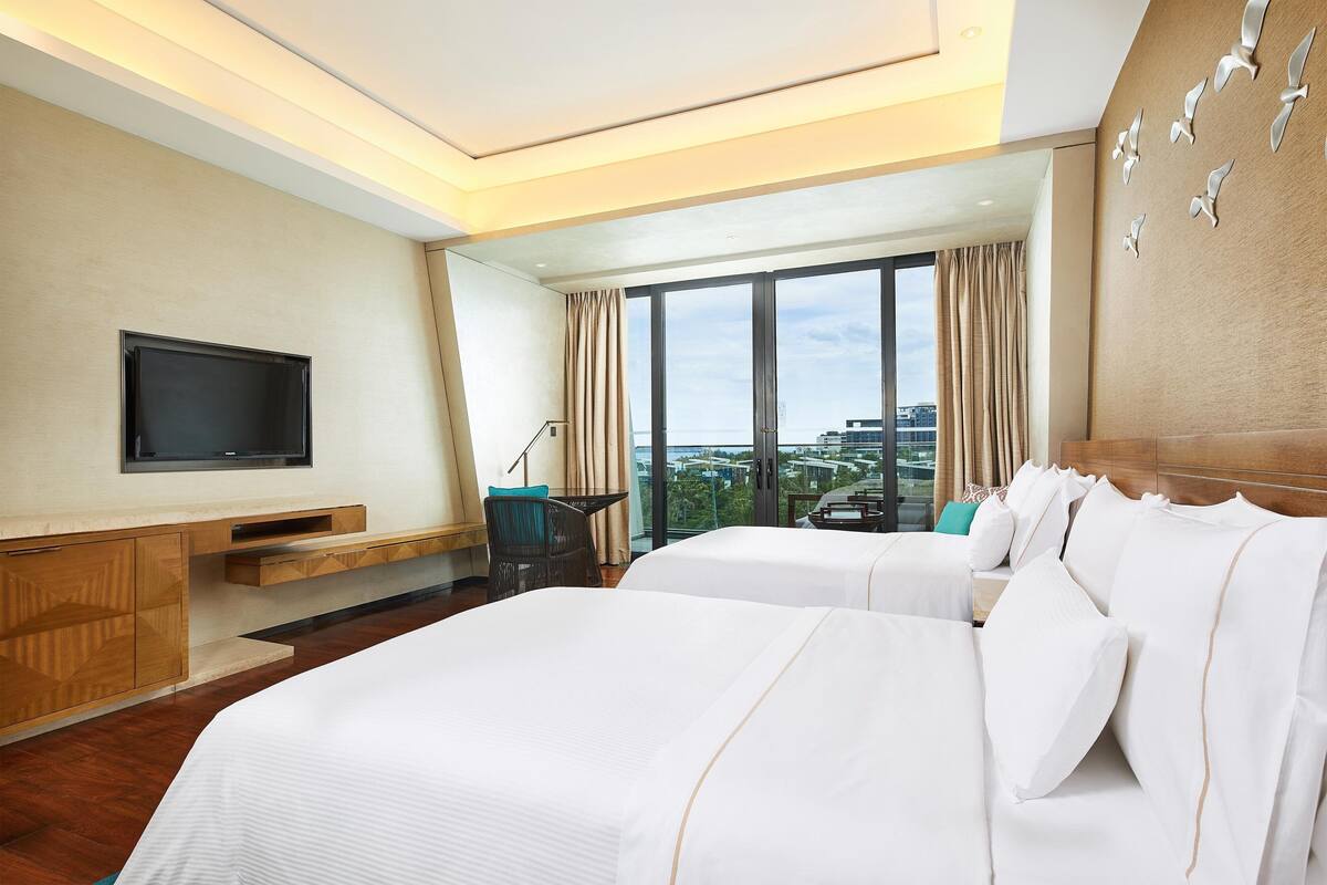 Une chambre d’hôtel avec deux lits, une télévision, un bureau et une vue sur la ville.