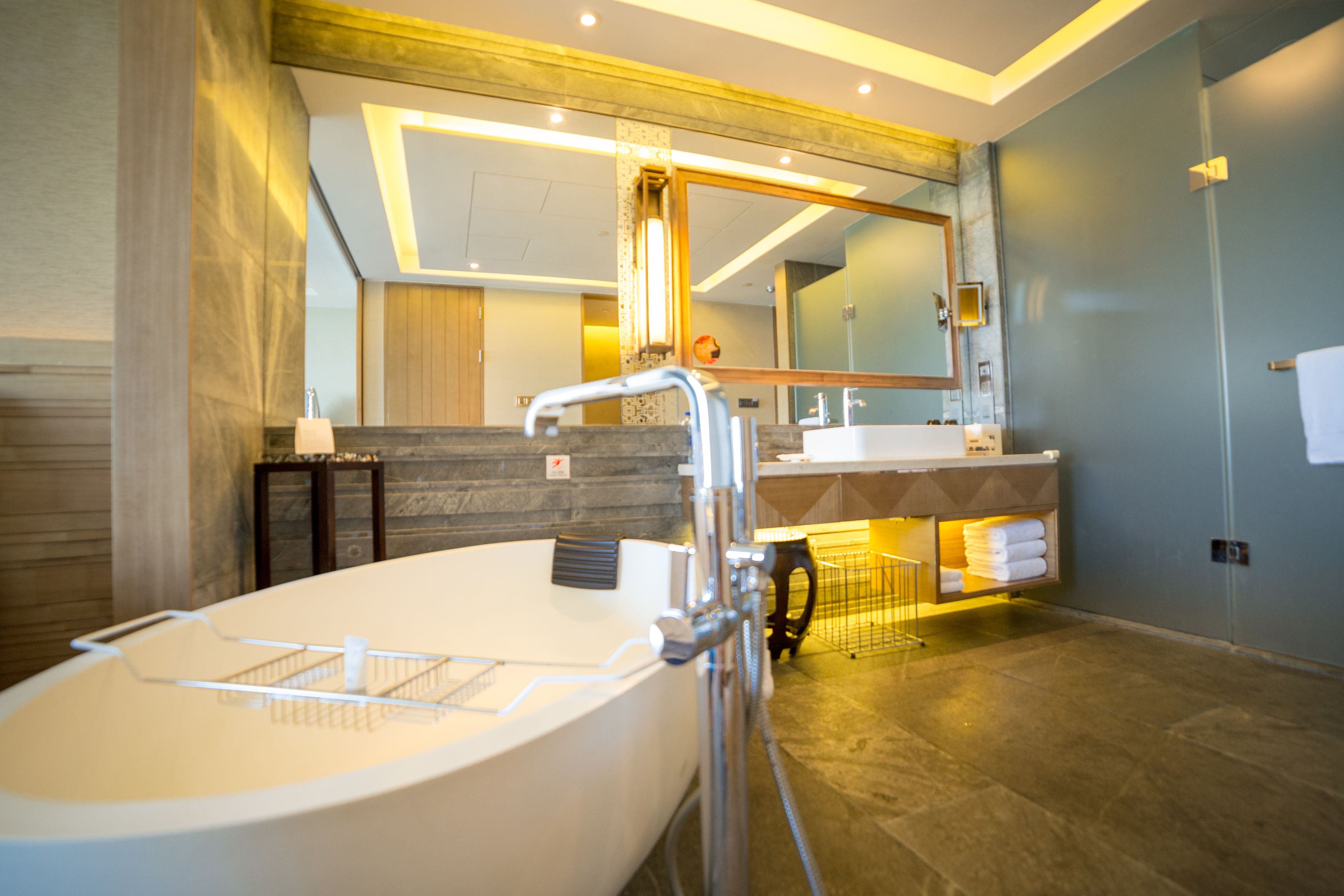 A modern bathroom with a freestanding bathtub, a large mirror, and a vanity with a towel rack.