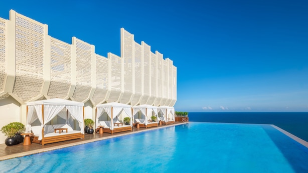 A poolside area with a series of white canopies and wooden loungers.