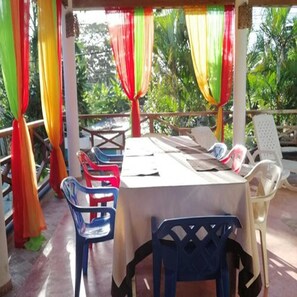 A covered outdoor seating area with a table and chairs, surrounded by colorful drapes. - House Jardin Del Caribe (Las Terrenas)