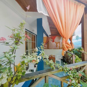 A covered outdoor area with a wooden railing, potted plants, and a view of the ocean. - House Jardin Del Caribe (Las Terrenas)