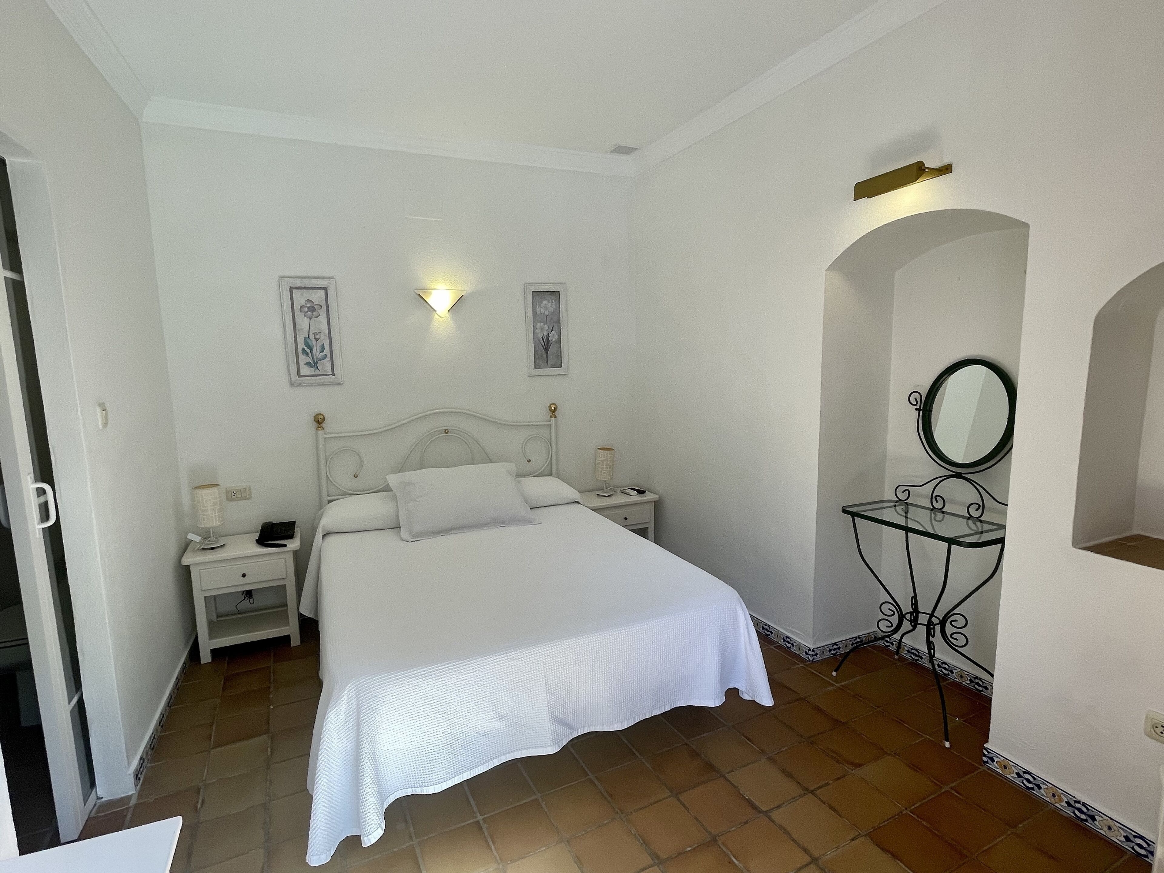 Une chambre à coucher comprenant un lit, des tables de chevet, une table de chevet avec une lampe et un miroir.