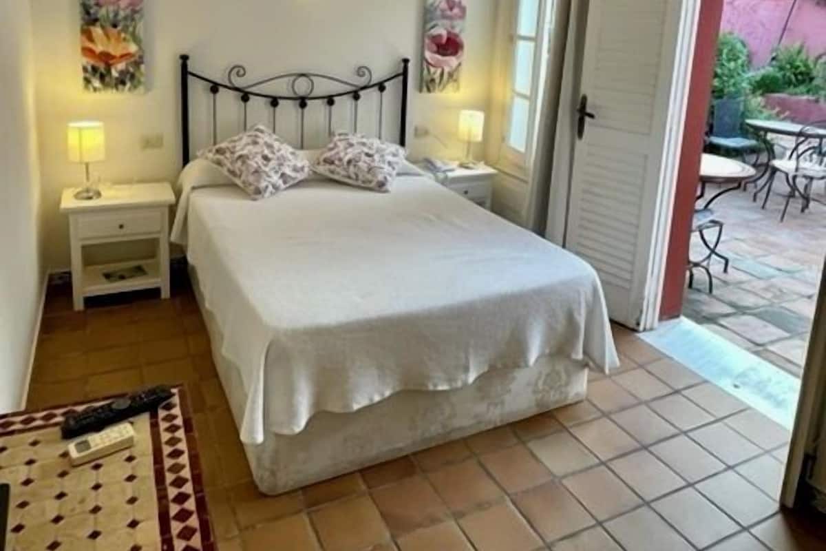A bedroom with a bed, bedside tables, and a view of the outside patio.