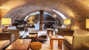 A cozy, rustic interior with wicker furniture, wooden tables, and a stone ceiling. - Hotel Es Port (Sóller)