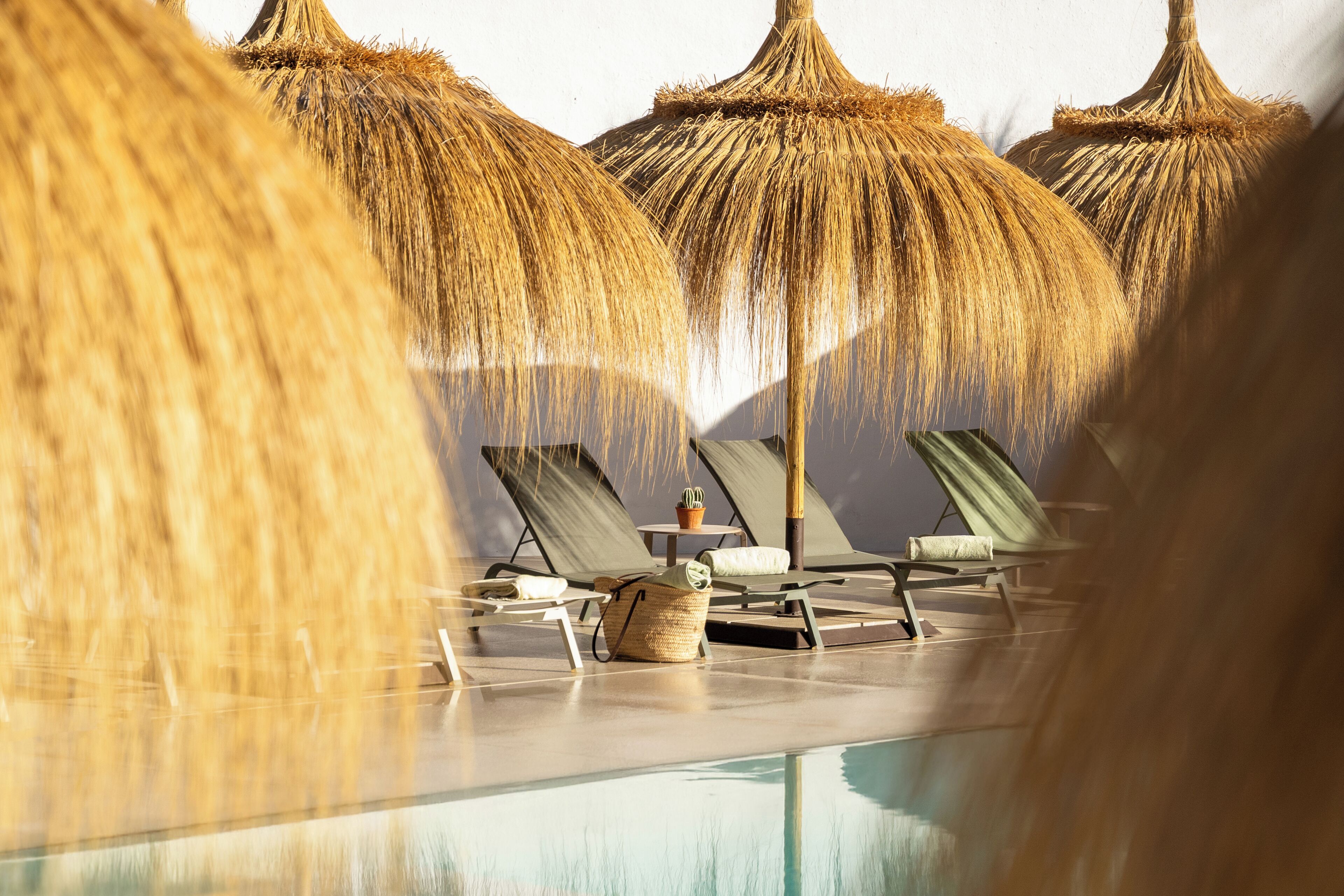 A poolside area with lounge chairs and thatched umbrellas.