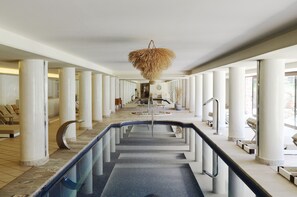 A hotel lobby with a central pool, white pillars, and a hanging decorative element.
