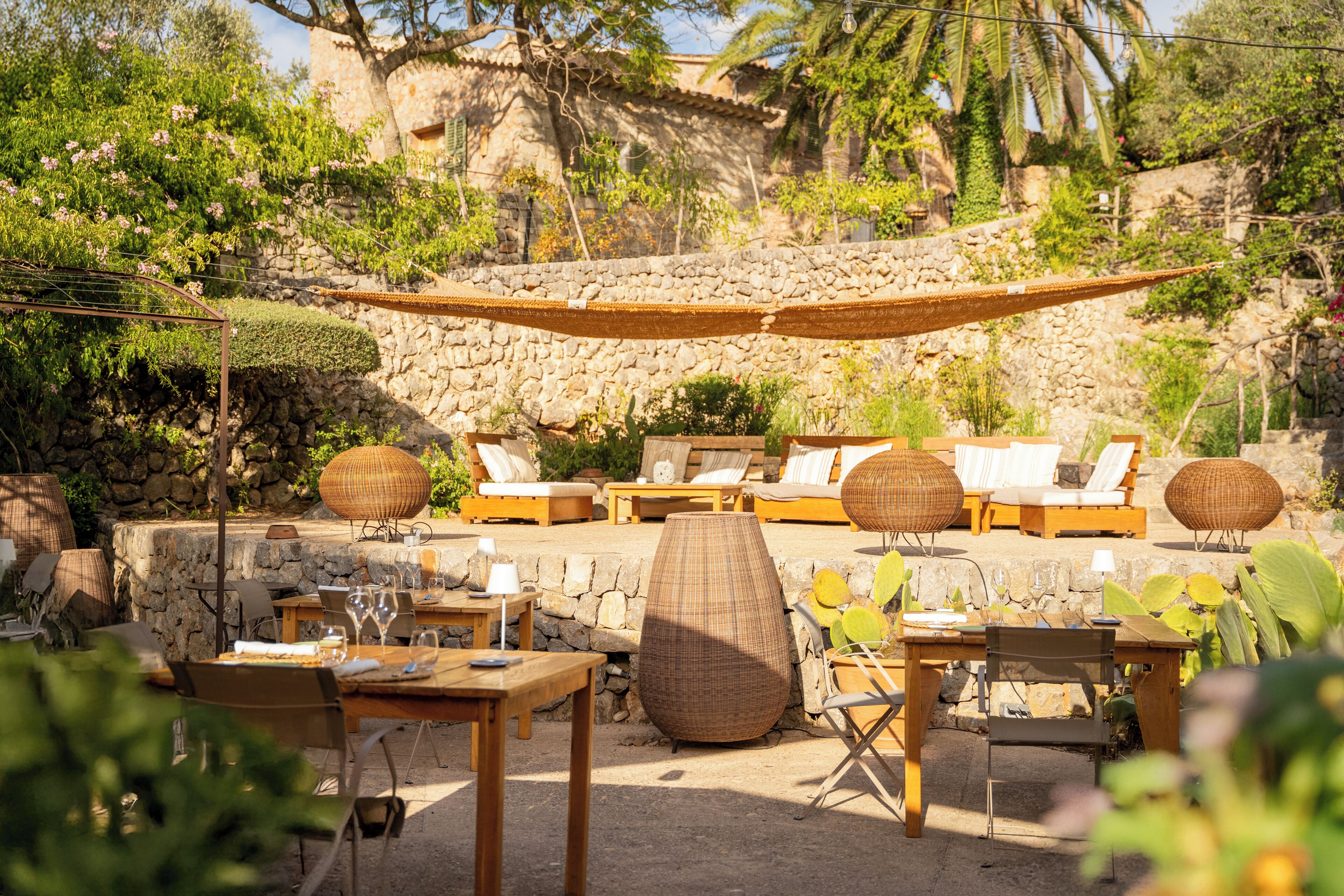 An outdoor seating area with wicker furniture, stone walls, and greenery.