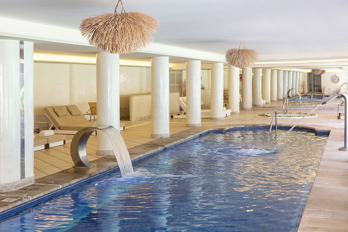 A spa area with a large pool, lounge chairs, and a waterfall feature.
