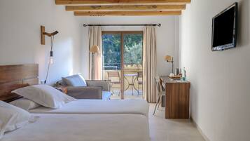 A hotel room with two beds, a desk, a chair, a TV, and a balcony with a table and chairs.