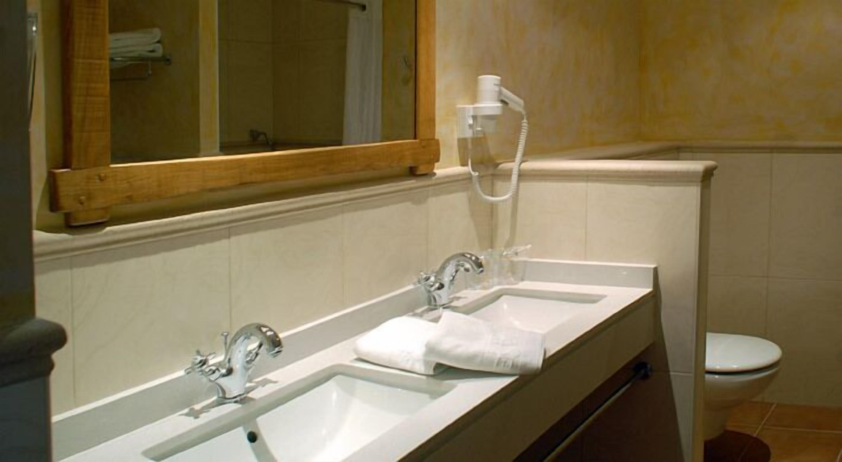 Une salle de bain avec deux lavabos, un miroir, des toilettes et une douche.