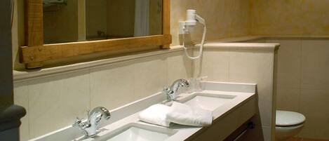 Une salle de bain avec deux lavabos, un miroir, des toilettes et une douche.