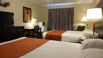 Une chambre d’hôtel avec deux lits, un bureau, une télévision et un ventilateur de plafond.