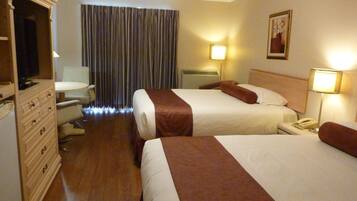 Habitación de hotel con dos camas, un escritorio, una silla, un tocador y una ventana con cortinas.