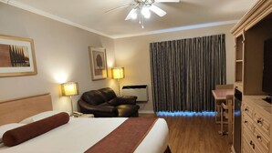 A hotel room with a bed, a desk, a chair, a wardrobe, and a curtain.
