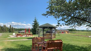 A gazebo with a picnic table and chairs in a grassy area.