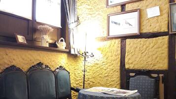Una habitación con un banco de madera, una mesa con mantel estampado y cuadros en la pared.