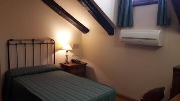 A bedroom with a bed, bedside table, lamp, and air conditioning unit.
