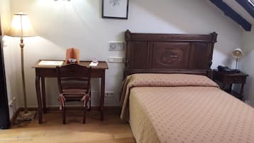 Un dormitorio con una cama de madera, un escritorio con silla, una lámpara y un cuadro en la pared.