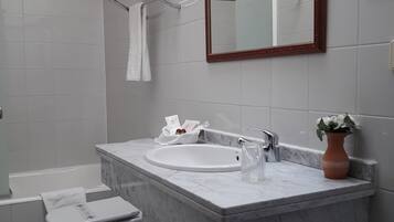 Un baño con inodoro blanco, lavamanos, espejo y ducha.