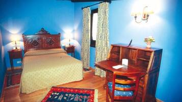 Un dormitorio con cama, mesitas de noche, un escritorio y una silla.