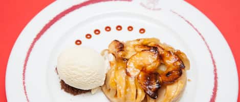 Une assiette de dessert avec une tarte aux pommes caramélisées et une boule de glace à la vanille.