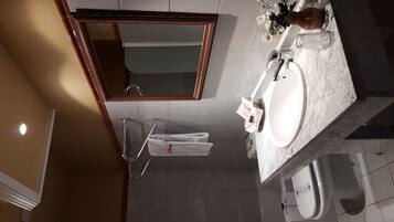 Un baño moderno con un espejo grande, un lavabo y un inodoro.