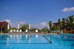 Una piscina al aire libre, sombrillas, sillones reclinables de piscina