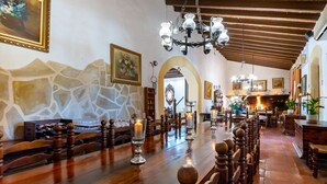Una larga mesa de comedor de madera con candelabros, rodeada de sillas de madera.