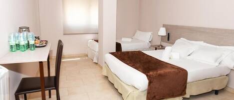 Una habitación de hotel con cama, escritorio, silla y ventana.