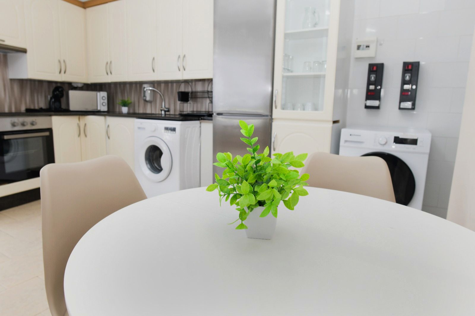 A modern kitchen with white cabinets, a microwave, a washing machine, and a refrigerator.
